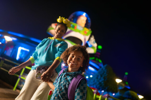 A son and mum walk in front of the Buzz Lightyear statue at Hollywood Studios at nighttime