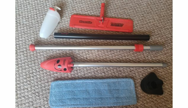 The disassembled Henry Spray Mop laid out on a beige carpeted floor. Image includes 400ml spray bottle 40cm floor head Spray Mop pad Plastic foot pedal Three part handle