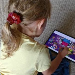 A young girl in a yellow t-shirt plays Time Table Rockstars on the Lenovo Tab P12 and Tab Pen Plus