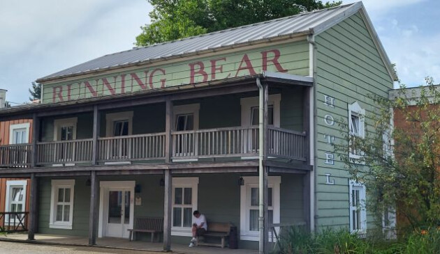 A green wooden building with the words 'Running Bear Hotel' written on the side