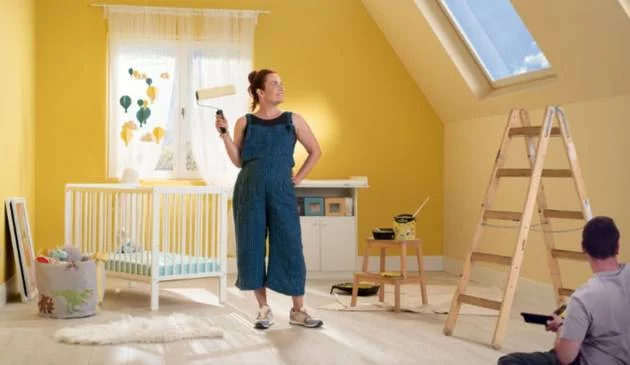 Parents painting a newborn's nursery with Crown paint