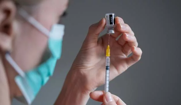 A nurse holds a vaccination needle