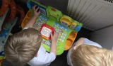 Two children play with the Vtech Touch & Learn Activity Desk