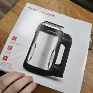 A hand holds the Morphy Richards Saute and Soup Maker box