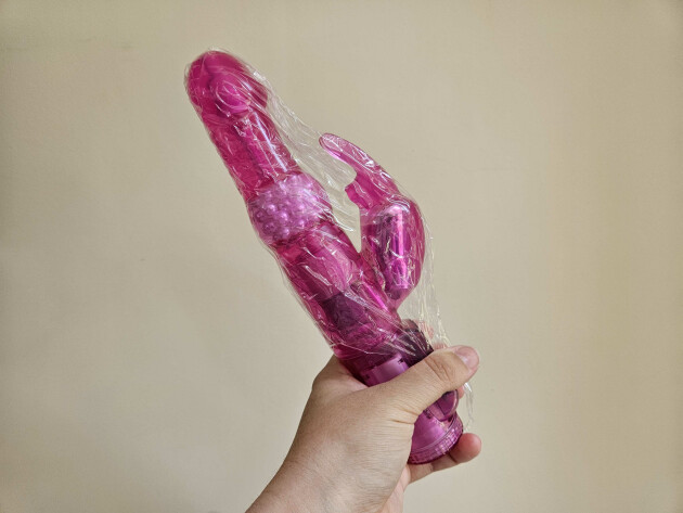 A picture of a hand holding Lovehoney's Jessica Rabbit vibrator wrapped in shrink wrap