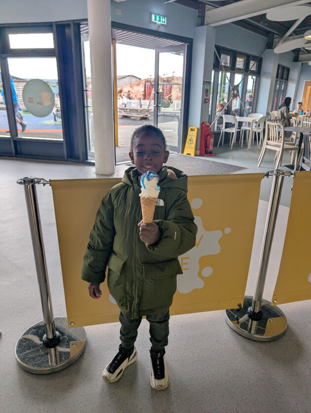 Yvonne's son smiles at the camera with a huge ice cream in his hand