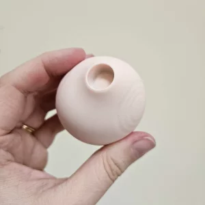 A hand holding the HANX Cindy against a wall