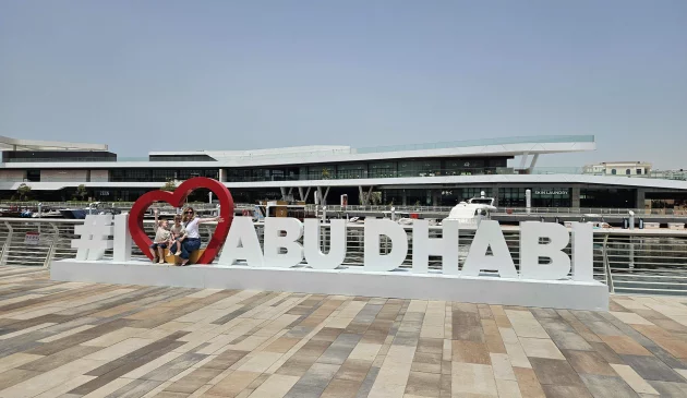 Rebecca Roberts and her two children sit atop the I love Abu Dhabi sign in Al Qana marina in Abu Dhabi