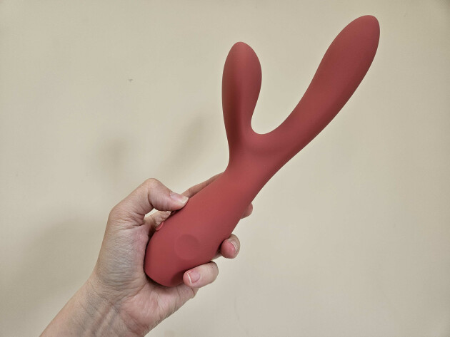 A hand holds The Smile Maker's The Artist dual motor vibrator against a wall