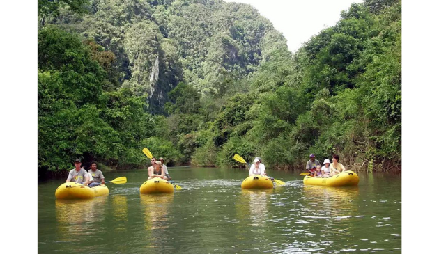 four people in yellow kayaks with mountains in the background