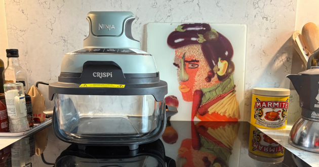 Ninja CRiSPi portable cooking system on kitchen counter next to decorative art and Marmite jar