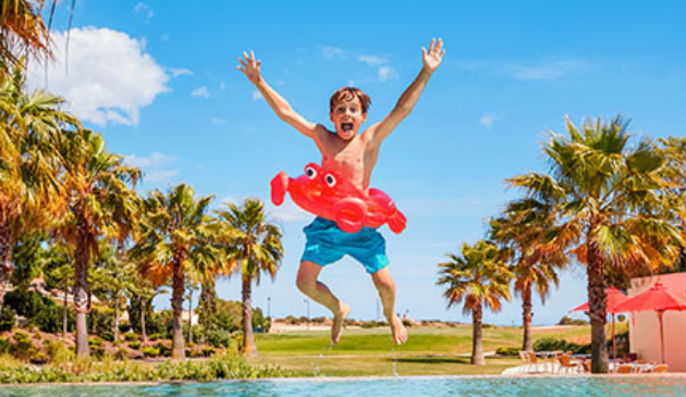 a boy with a red rubber ring jumping into a pool