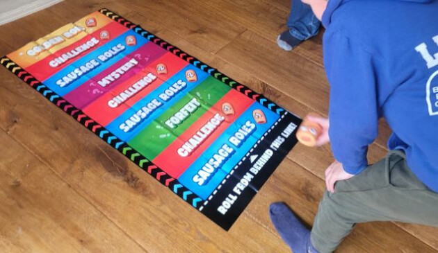 An older boy in a blue sweatshirt playing the Sausage Roll Party Game