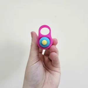 A hand holding the Lovehoney Excite 10 Function Finger Vibrator against a wall