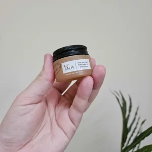 UpCircle Lip Balm Under the Mistletoe stocking filler gift being held by Mumsnet editor Rebecca against a wall