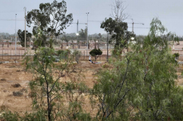 View from the resort towards dry open land, scattered trees, streetlights and construction cranes in the distance.