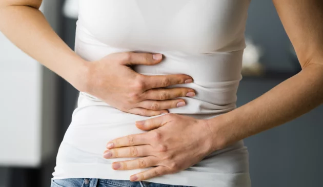 A woman holds her stomach because she's constipated