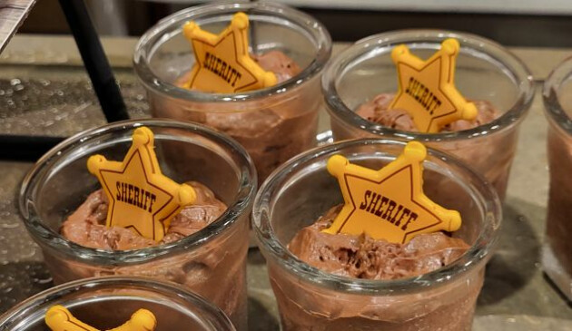 Individual pots of chocolate mouse with yellow sheriff badges on top