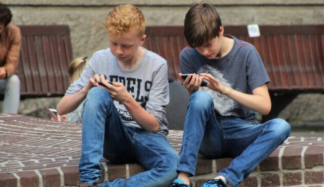 Two teenage boys engrossed in their smartphones