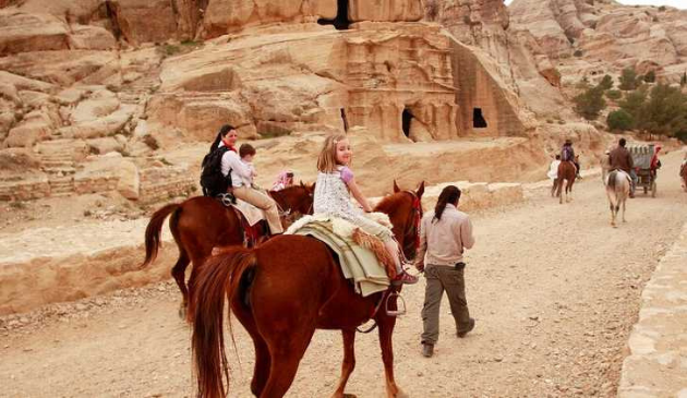 a family group riding horses in a desert
