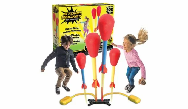 A boy and a girl are pictured mid-jump attempting to launch the red, yellow and blue Stomp Rockets between them. The yellow and black product box is behind this main image.