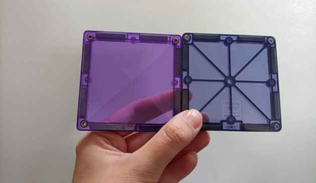 A hand holds a Connetix magnetic tile and a Magna-Tile