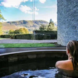 a woman in a hot tub looking at a mountain view