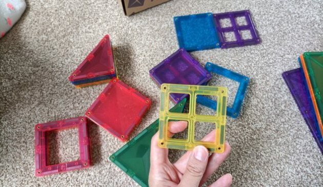 A hand holding a yellow window magnetic tile