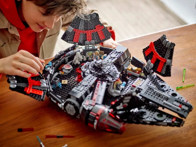 A young boy builds LEGO's Star Wars The Dark Falcon