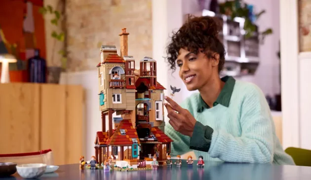 A woman building The Burrow - Collector's Edition LEGO Harry Potter set