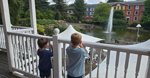 Two children looking over the hotel balcony towards the lake and fountain