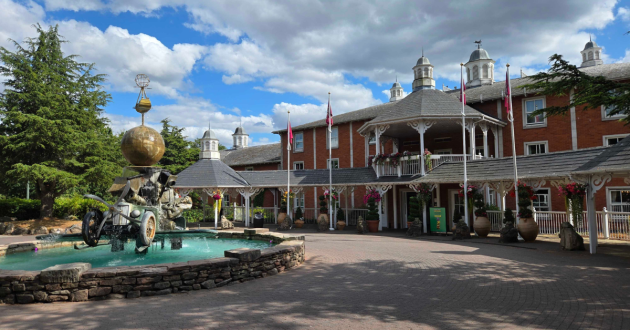 Front exterior of Alton Towers Hotel with red-brick façade, white veranda and themed fountain