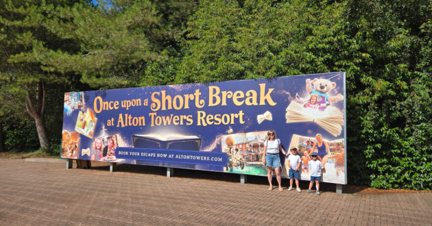 Family standing beside an Alton Towers Resort short-break advertising board