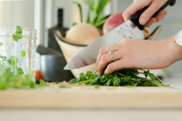 A woman makes a salad on a chopping board