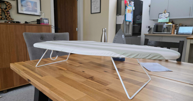 Side view of Argos Home Table Top Ironing Board with folding legs open on a dining table