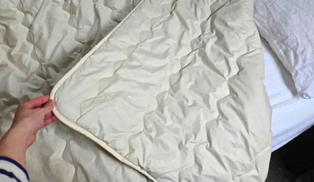 Close-up of the Ava Innes Luxury Cashmere and Wool Duvet showing the flat loft and signature S-stitch quilting in certified organic cotton casing.