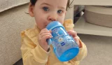 Baby holding MAM Trainer+ cup