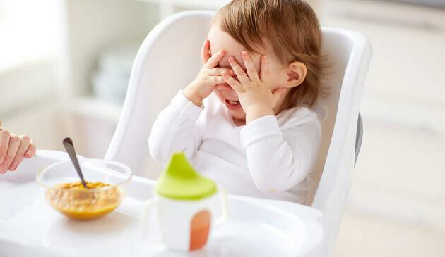 child playing hide and seek in highchair