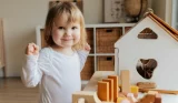 Toddler playing with a dolls' house