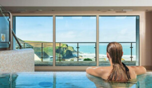 Woman in a spa pool overlooking Mawgan Porth beach from the Bedruthan Hotel and Spa