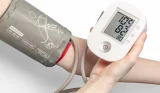 Woman takes her blood pressure at home using an arm cuff
