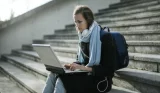woman on laptop sat on steps