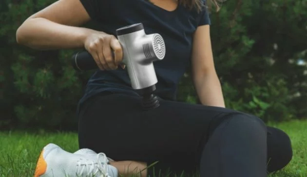 woman using sports massage gun after workout