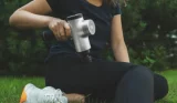 woman using sports massage gun after workout