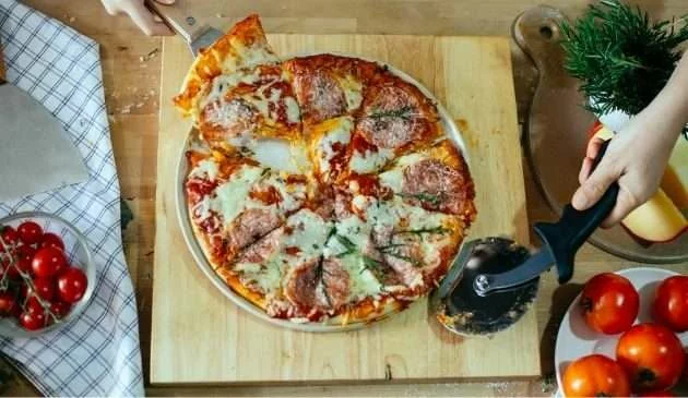 Family using cutter for pizza