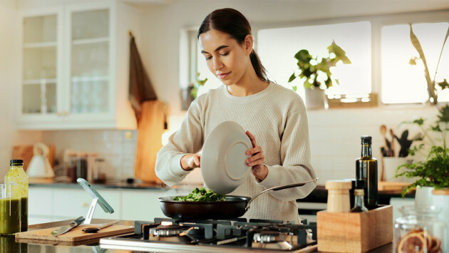 A woman makes a healthy meal on her stove top at home