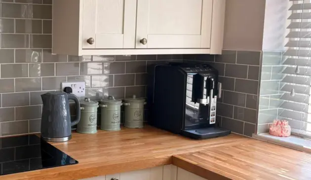 Black Bosch Series 2 VeroCafe bean-to-cup coffee machine on a wooden kitchen worktop beside a kettle and storage jars