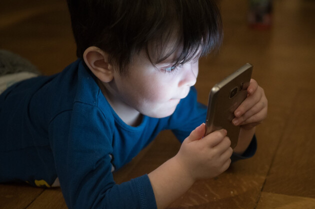 A very young boy staring at a mobile phone screen