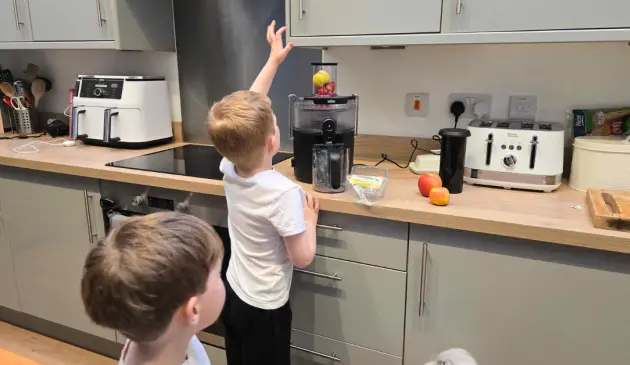 Two children help add fruits to the Braun MultiJuice 5 spin juicer during testing