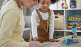 Child and adult playing with wooden blocks
